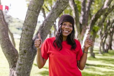 Smiling woman in a red shirt enjoying a sunny day outdoors in a park.