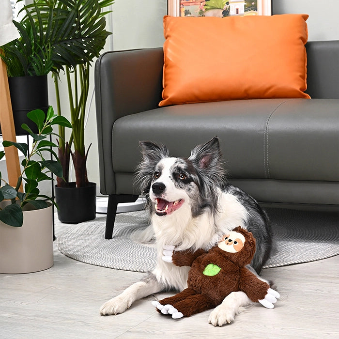 A border collie lies on a rug next to a brown Hugsmart Jungle Tails sloth plush dog toy.