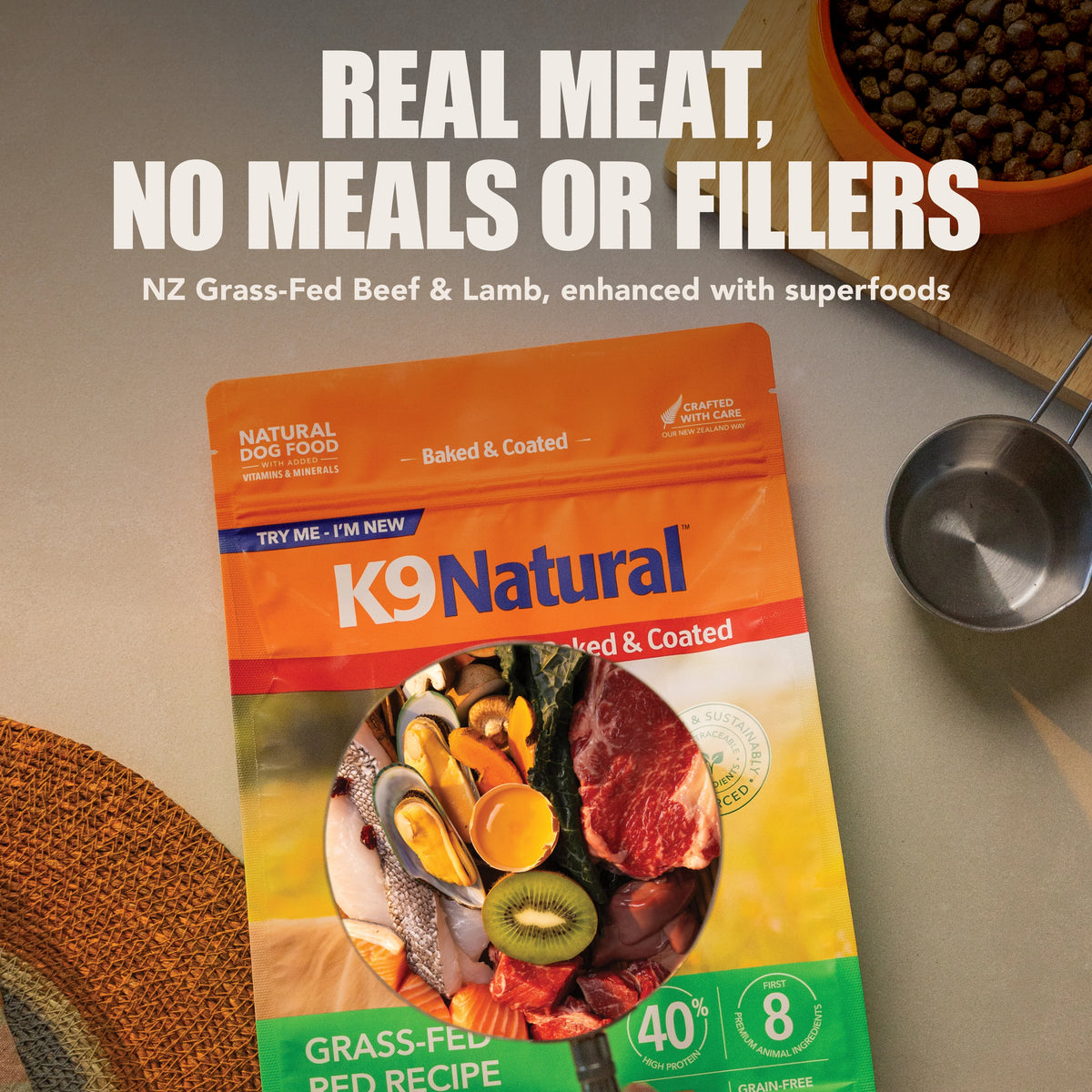 K9 Natural Baked & Coated Grass-Fed Red Dog Food bag with fresh ingredients and a bowl of kibble.