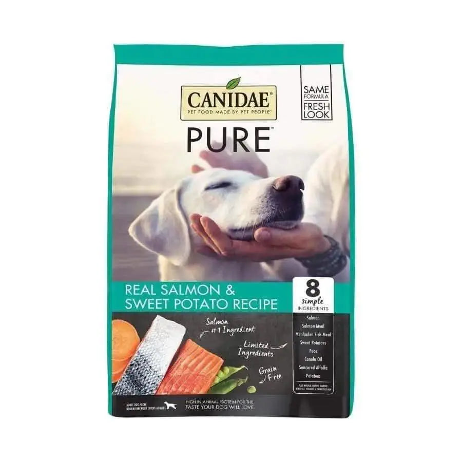 CANIDAE PURE Grain-Free Real Salmon & Sweet Potato Recipe Dry Dog Food features a white dog being gently held, with salmon and sweet potato images, and highlights limited ingredients for gentle nutrition.