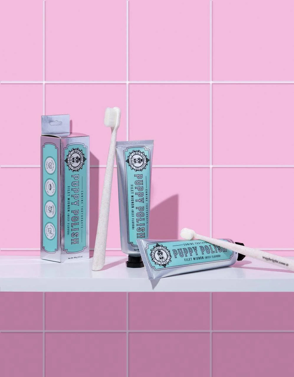 Wag & Bright Puppy Polisher Eco Toothbrush and Puppy Polish toothpaste on a pink tiled background.