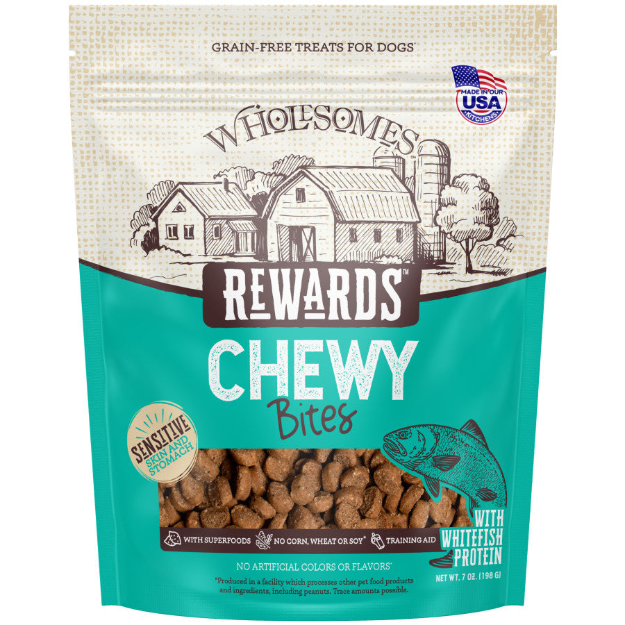 Talis Us Wholesomes Chewy Whitefish Dog Treats in a teal and brown bag, featuring a farm illustration and fish graphic.
