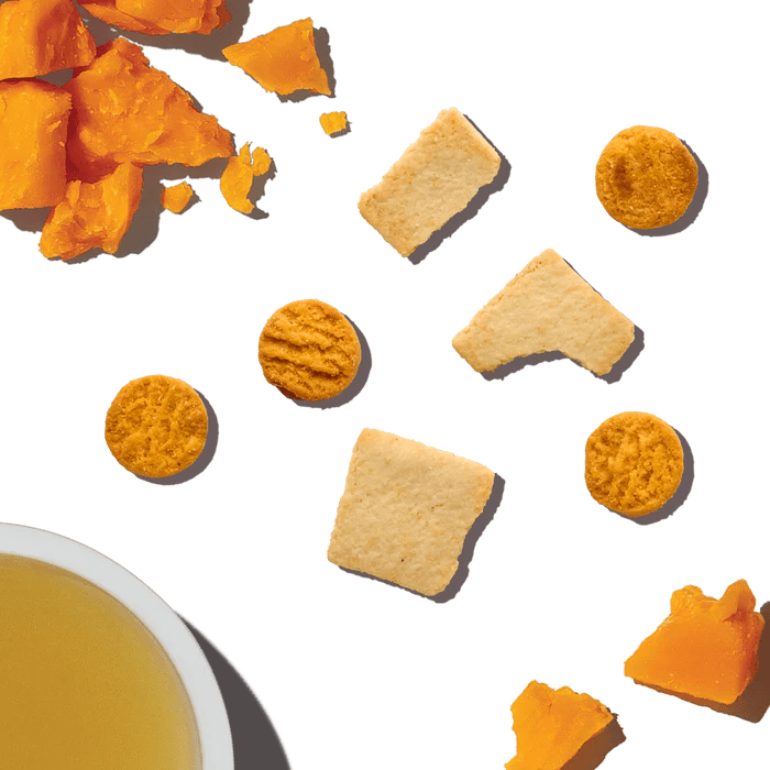 Cheese and crackers dog treats by The Honest Kitchen displayed with ingredients and treats on a black background